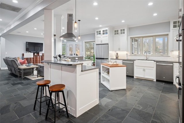 kitchen with visible vents, appliances with stainless steel finishes, a center island, tasteful backsplash, and island exhaust hood