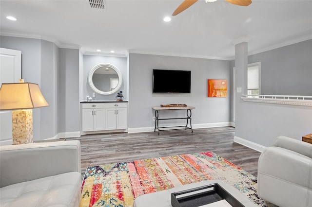 living room featuring crown molding, visible vents, a ceiling fan, wood finished floors, and baseboards