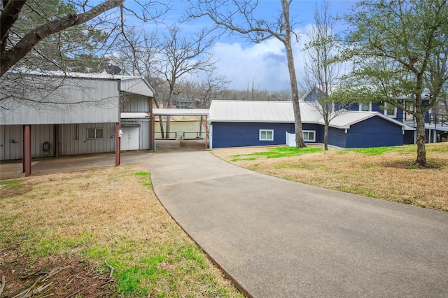 exterior space with metal roof, concrete driveway, and a front yard