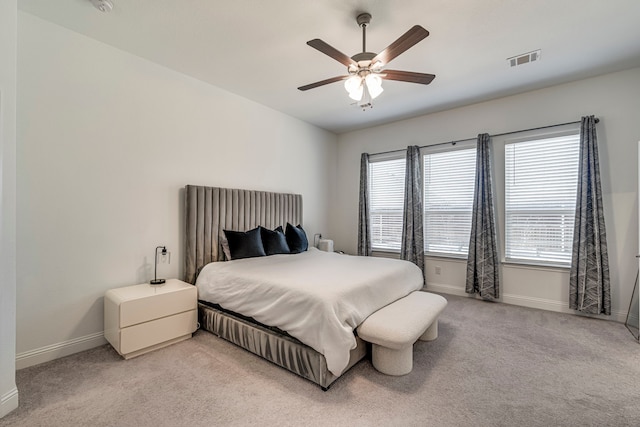 bedroom with baseboards, a ceiling fan, visible vents, and light colored carpet