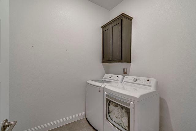 clothes washing area featuring washer and dryer, cabinet space, baseboards, and light tile patterned flooring