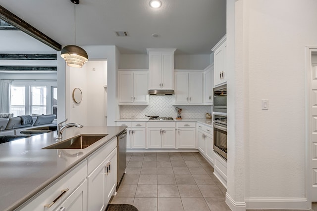 kitchen with tasteful backsplash, stainless steel appliances, under cabinet range hood, white cabinetry, and a sink