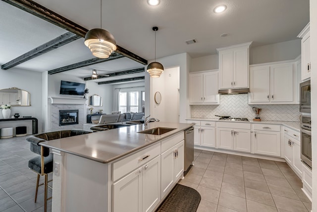 kitchen featuring stainless steel appliances, a sink, visible vents, tasteful backsplash, and a glass covered fireplace