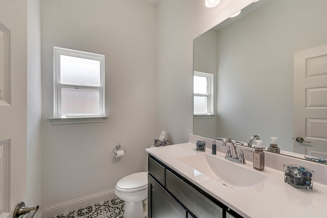 half bath with baseboards, vanity, and toilet