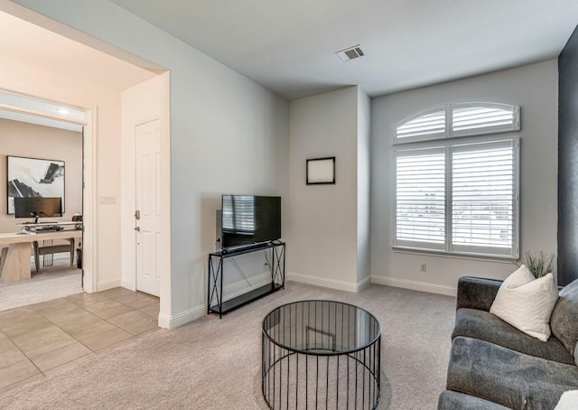 living room featuring tile patterned flooring, visible vents, baseboards, and carpet flooring