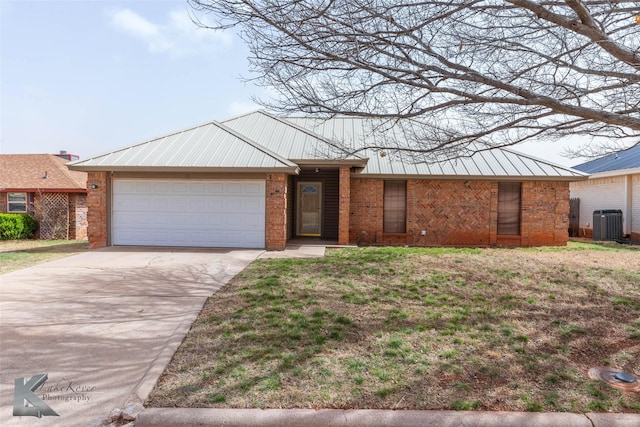 view of front of house featuring metal roof, a garage, central AC, brick siding, and driveway