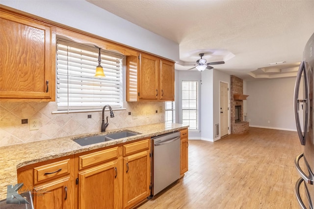 kitchen with a fireplace, stainless steel appliances, tasteful backsplash, a ceiling fan, and a sink