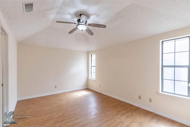 spare room featuring light wood-style floors, visible vents, ceiling fan, and baseboards