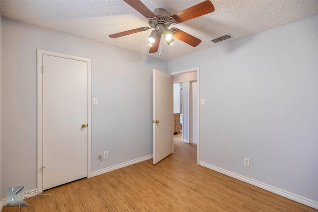 unfurnished bedroom with visible vents, light wood-style flooring, a ceiling fan, a textured ceiling, and baseboards