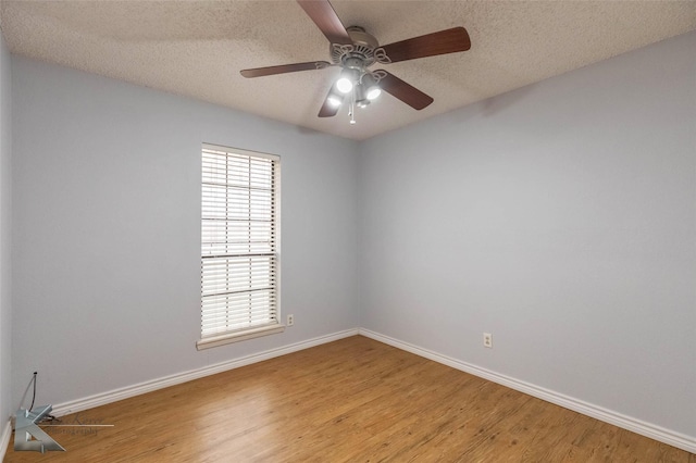 empty room with light wood-style floors, baseboards, and a textured ceiling