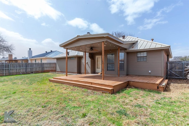 back of house with a lawn, metal roof, a deck, ceiling fan, and a fenced backyard