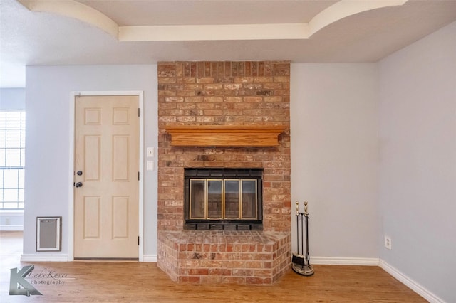 unfurnished living room featuring a fireplace, baseboards, and wood finished floors