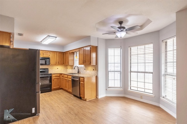 kitchen featuring light countertops, visible vents, a sink, light wood-type flooring, and black appliances