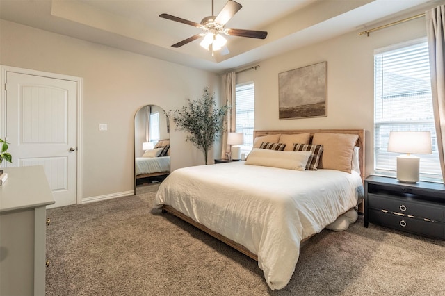 bedroom with arched walkways, a tray ceiling, carpet, and multiple windows