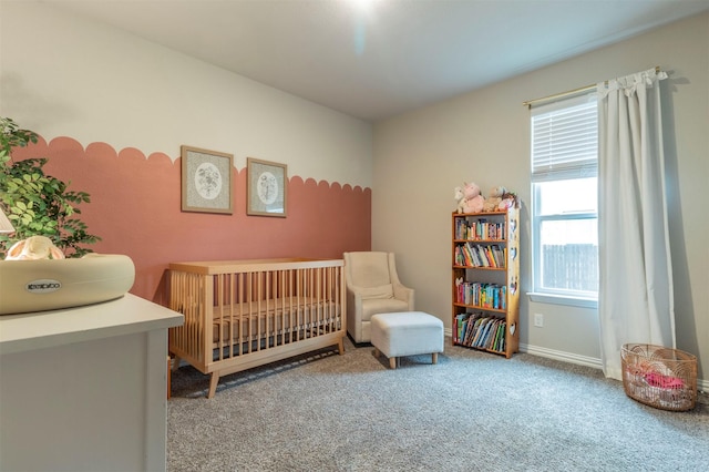 carpeted bedroom featuring a crib and baseboards