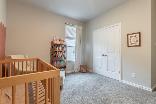 carpeted bedroom featuring a nursery area and baseboards