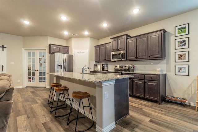 kitchen featuring a breakfast bar area, dark brown cabinetry, stainless steel appliances, a sink, and french doors