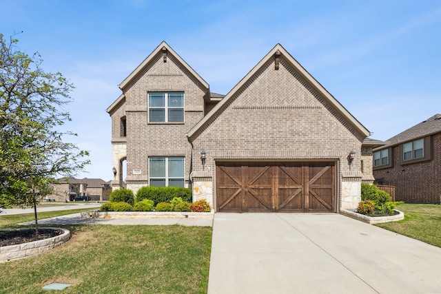 view of front of property featuring brick siding, an attached garage, stone siding, driveway, and a front lawn