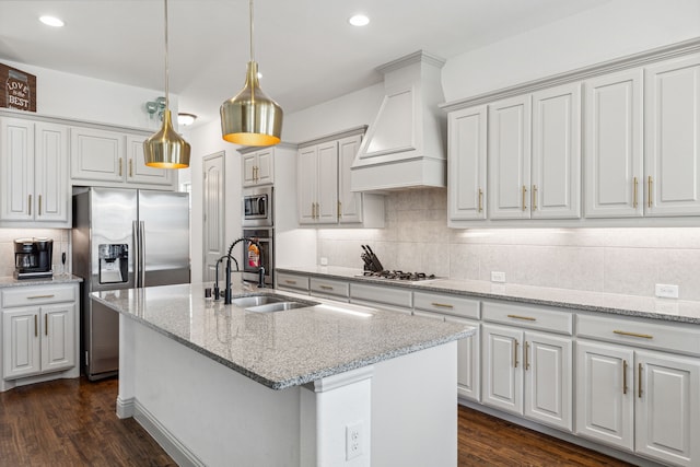 kitchen featuring tasteful backsplash, dark wood finished floors, appliances with stainless steel finishes, custom exhaust hood, and a sink