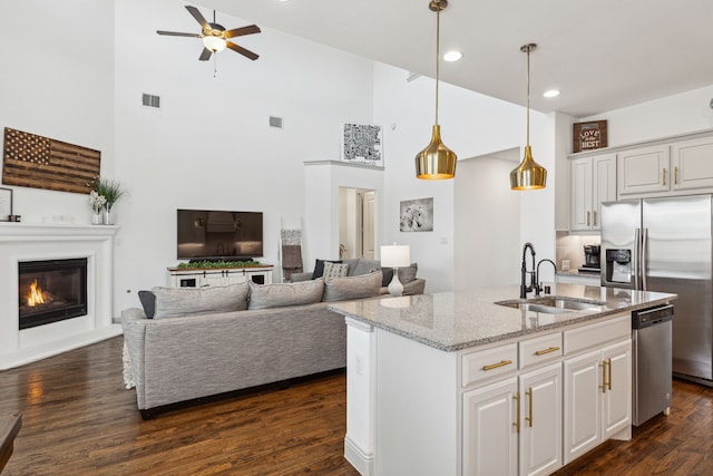 kitchen featuring a glass covered fireplace, light stone counters, dark wood-style flooring, stainless steel appliances, and a sink