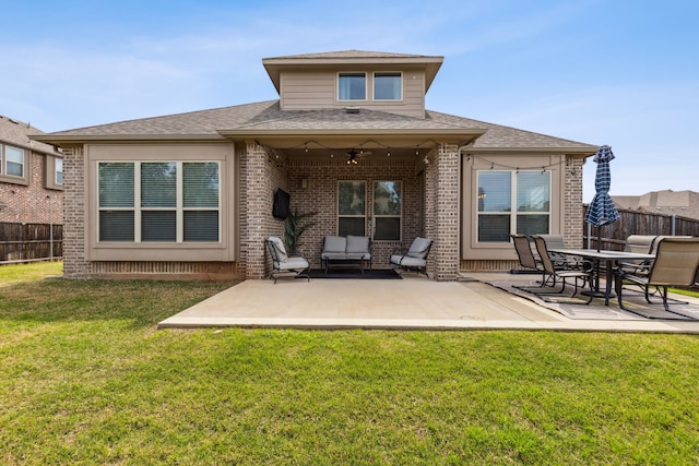 rear view of property featuring brick siding, a yard, a patio area, fence, and ceiling fan