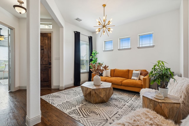 living room with an inviting chandelier, wood finished floors, visible vents, and baseboards