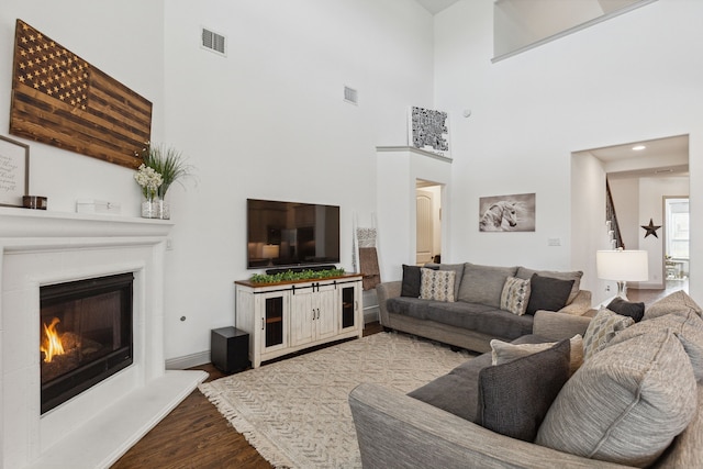 living room featuring a glass covered fireplace, visible vents, and wood finished floors