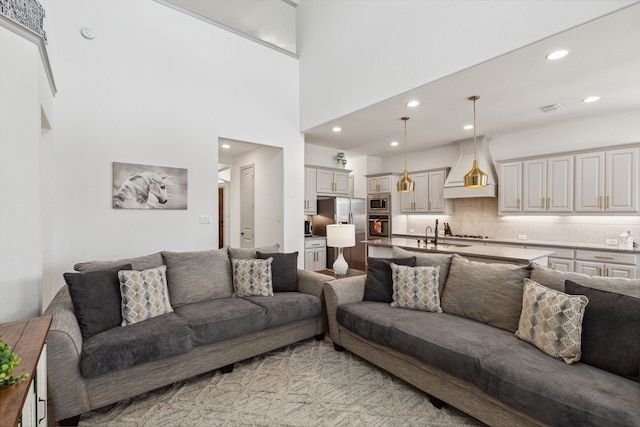 living area with recessed lighting, visible vents, and a towering ceiling