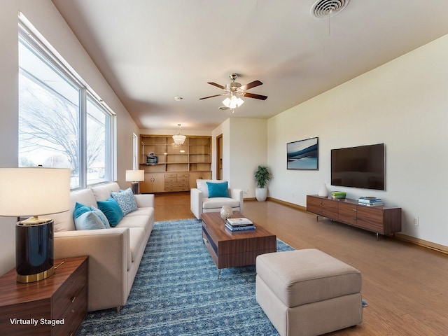 living room with a ceiling fan, wood finished floors, visible vents, and baseboards