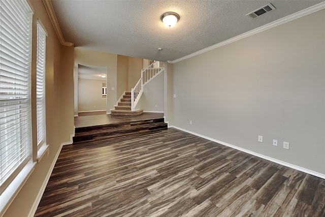 unfurnished room with crown molding, visible vents, dark wood-type flooring, a textured ceiling, and stairs