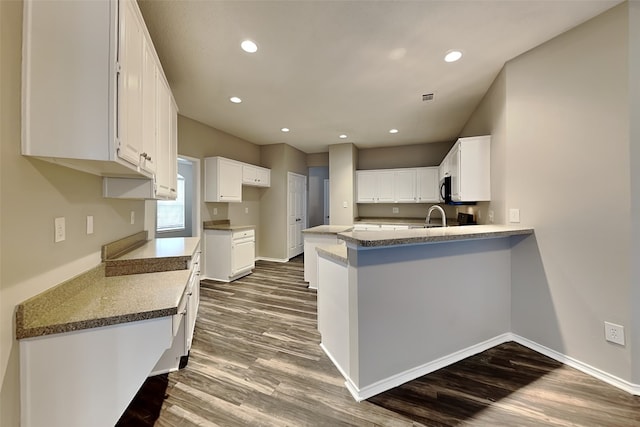 kitchen with baseboards, a peninsula, dark wood-type flooring, and recessed lighting