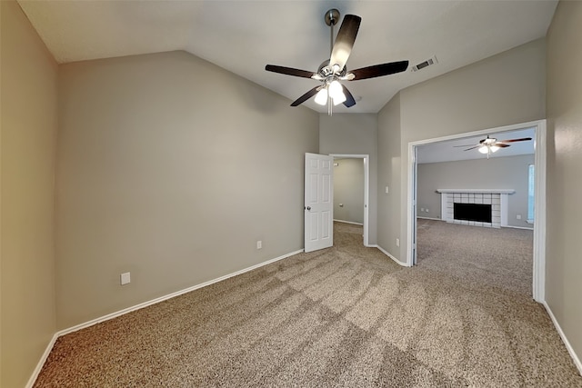 unfurnished bedroom featuring baseboards, visible vents, a tile fireplace, vaulted ceiling, and carpet floors