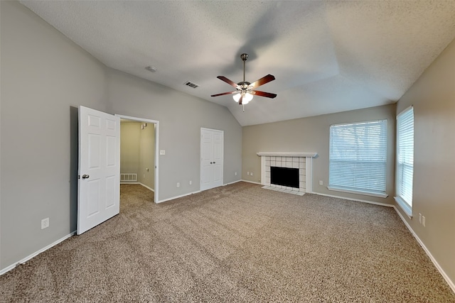 unfurnished living room with lofted ceiling, visible vents, carpet flooring, a textured ceiling, and a tile fireplace