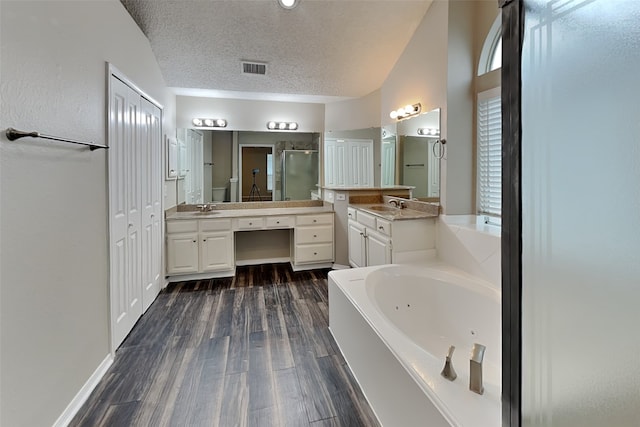 bathroom featuring a stall shower, wood finished floors, a jetted tub, vaulted ceiling, and a textured ceiling