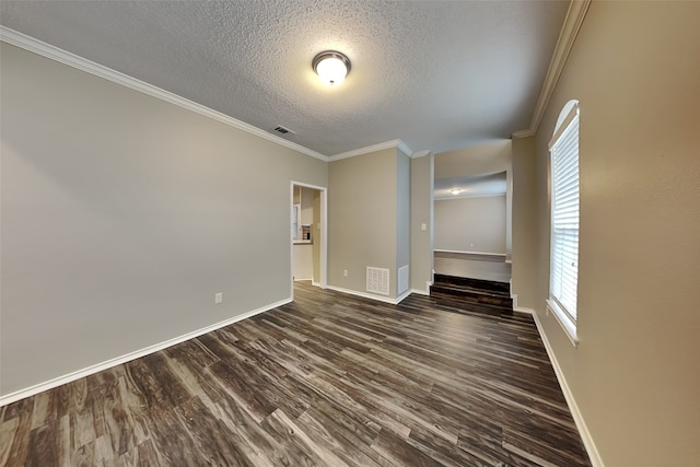 empty room featuring a textured ceiling, dark wood finished floors, visible vents, and crown molding