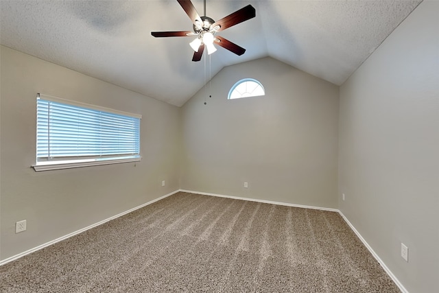 empty room with a textured ceiling, carpet floors, a ceiling fan, baseboards, and vaulted ceiling