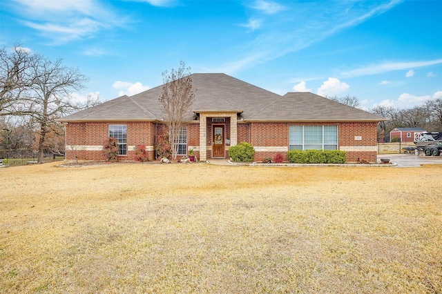 view of front of property with a shingled roof, a front yard, and brick siding