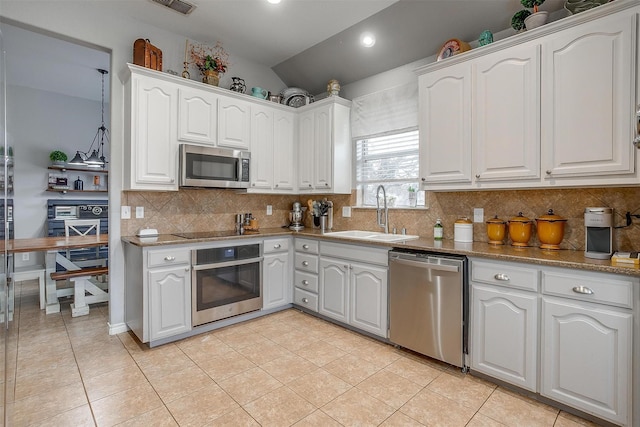 kitchen with light tile patterned floors, lofted ceiling, appliances with stainless steel finishes, white cabinets, and a sink