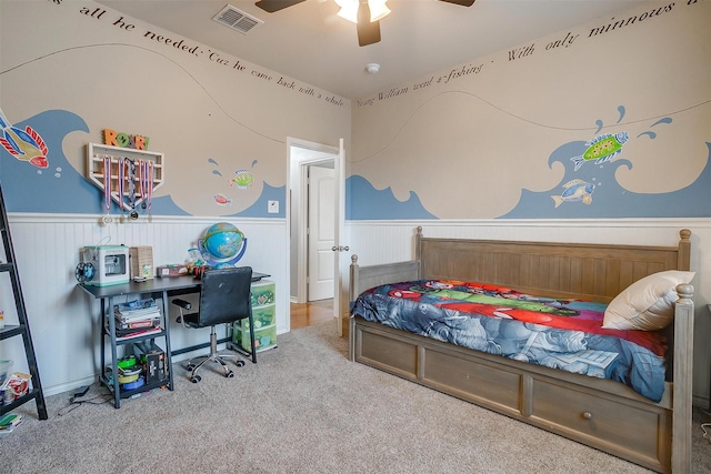 carpeted bedroom with wainscoting, visible vents, and ceiling fan