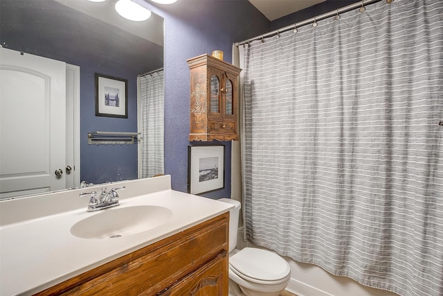 full bathroom with a textured wall, vanity, and toilet