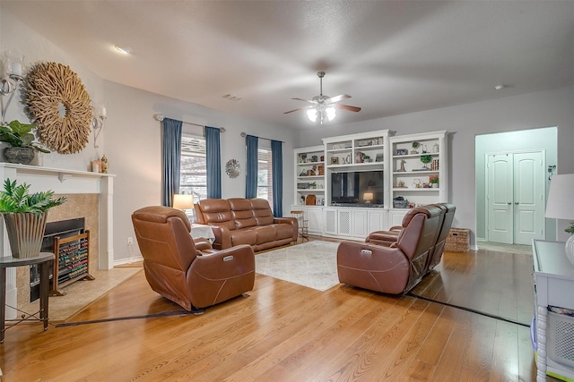 living area with a ceiling fan, a fireplace, visible vents, and light wood-style floors