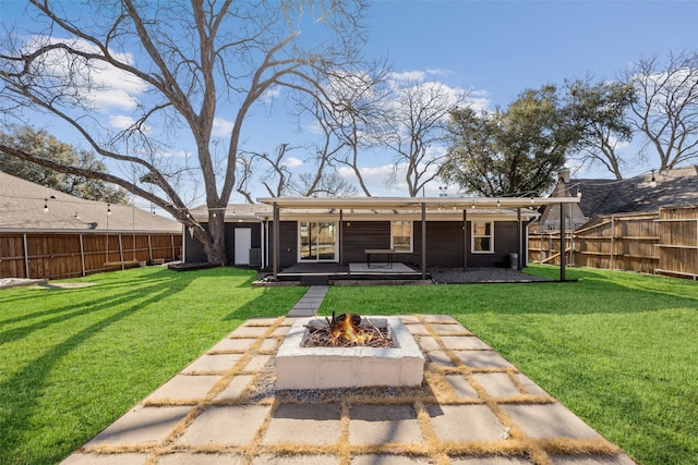 back of property featuring a fire pit, a yard, a patio, and a fenced backyard