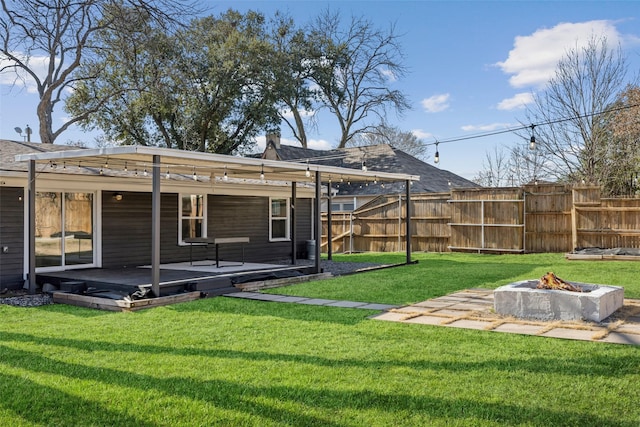 back of house with an outdoor fire pit, fence, a lawn, and a wooden deck