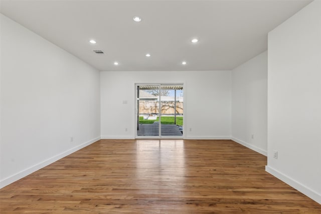 empty room featuring baseboards, visible vents, wood finished floors, and recessed lighting