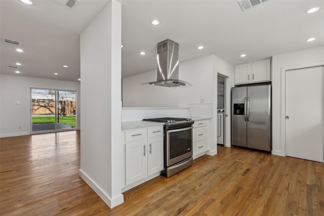 kitchen featuring appliances with stainless steel finishes, range hood, white cabinets, and visible vents