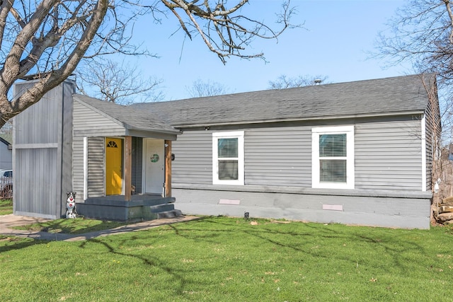 view of front of home with a shingled roof, a front lawn, and brick siding