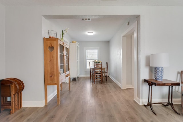 dining space featuring visible vents, light wood-style flooring, and baseboards