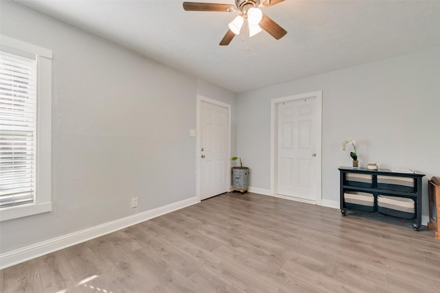 spare room featuring a ceiling fan, a healthy amount of sunlight, light wood-style flooring, and baseboards