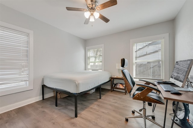 bedroom featuring ceiling fan, light wood-style flooring, and baseboards