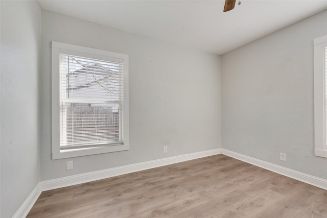 unfurnished room featuring plenty of natural light, light wood-style flooring, and baseboards